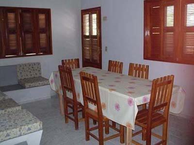 uma sala de jantar com uma mesa e cadeiras de madeira em Residencial Recanto do Paraiso em Jericoacoara