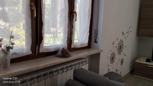 a window with curtains and a chair in a room at A casa di 'Nuccia' in Foglizzo