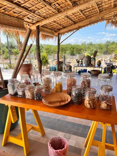 a wooden table with jars of food on it at Bently farm retreat Mũi Né-Premium Bungalow-05 in Ấp Phú Hiệp