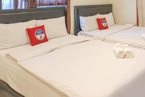 two beds with white sheets and red pillows at D Martin Malioboro Hotel RedPartner in Sentool