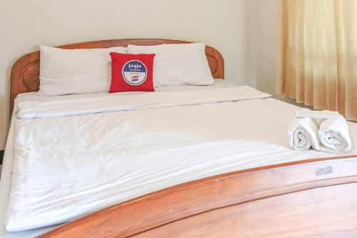 a bed with a red pillow and towels on it at D Martin Malioboro Hotel RedPartner in Sentool