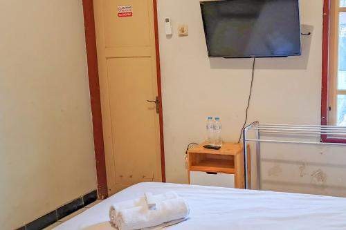 a room with a bed and a flat screen tv at D Martin Malioboro Hotel RedPartner in Sentool