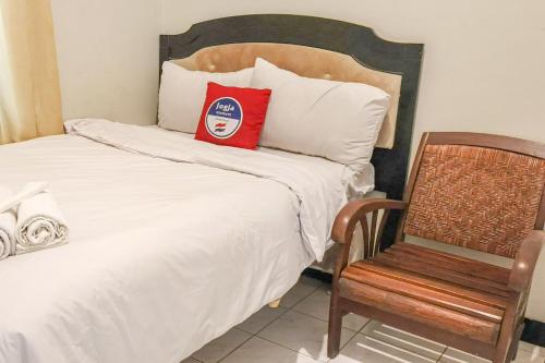 a bed with a red pillow and a chair at D Martin Malioboro Hotel RedPartner in Sentool
