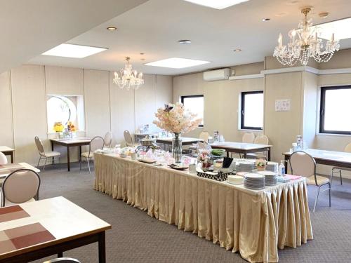 a large room with tables and chairs and chandeliers at ホテルロイヤル北見 in Kitami