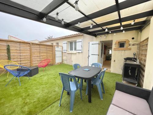 un patio avec une table et des chaises sur l'herbe dans l'établissement Maison rénovée 2 chambres, 700m plage, Accès WIFI - FR-1-231-335, à Bretignolles-sur-Mer
