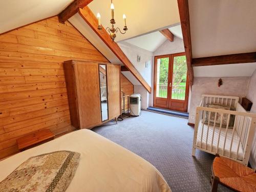 a bedroom with wooden walls and a crib in a house at Gîte Tourangelle avec Piscine Intérieure, Wifi, Jardin - FR-1-381-619 in Assay