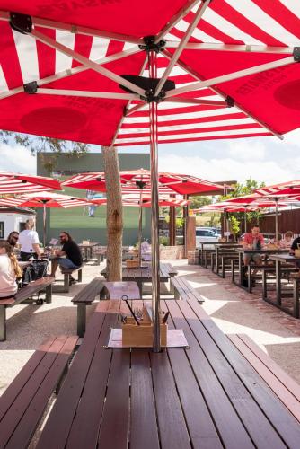 a picnic table with red umbrellas on top of it at Quality Hotel Bayswater in Perth
