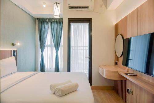 a bedroom with a bed and a flat screen tv at Stunning Studio Transpark Bintaro Apartment By Travelio in Tangerang