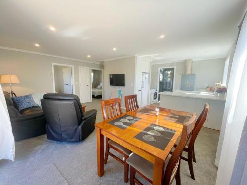 a dining room with a table and chairs and a living room at Brand new, close to hospital, plenty of parking sapces in Hamilton