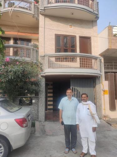 two men are standing in front of a building at Shri Devbhoomi homestay in Haridwār