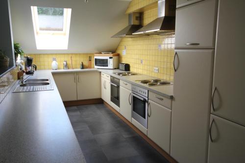 een keuken met witte apparatuur en gele tegels bij Cottage Olborbotte in Malmedy