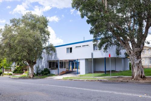 a white building with a blue roof on a street at Windsor Heritage Motel in Windsor
