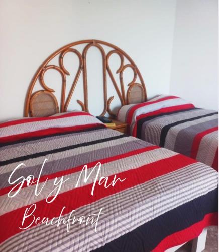 two beds with red white and blue striped blankets at Torres Gemelas Acapulco Suites in Acapulco
