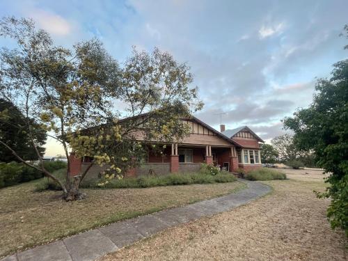 una casa de ladrillo rojo con un árbol delante en McIntyre homestead, en Penshurst