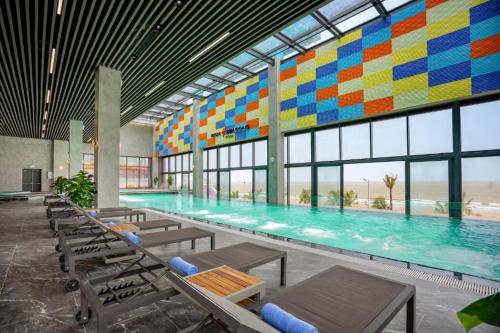 a large swimming pool with tables and chairs in a building at Flamingo Hai Tien in Nam Khê