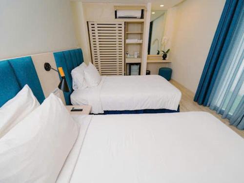 two beds in a hotel room with blue curtains at Oceanami Luxury Villa in Long Hai
