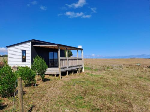 a tiny house with a porch in a field at Bergblick in Raglan