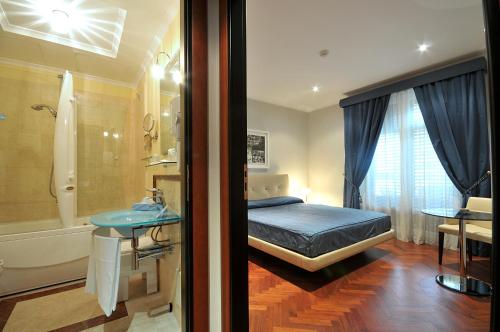 a bedroom with a bed and a bathroom with a tub at Hotel Giardino Inglese in Palermo