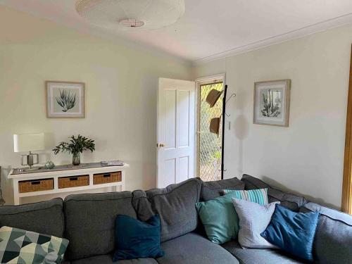a living room with a gray couch with blue pillows at Bayhaven- Best deal 4 bedroom 2 bathroom getaway in Port Moonta