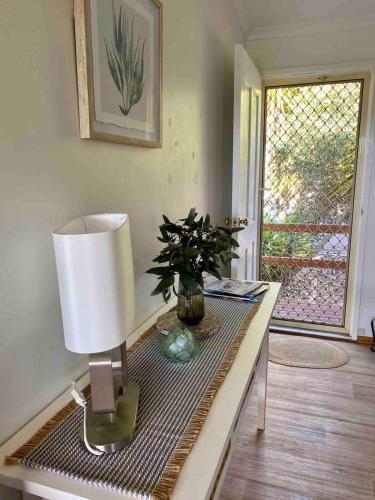 a table with a lamp and a plant on it at Bayhaven- Best deal 4 bedroom 2 bathroom getaway in Port Moonta