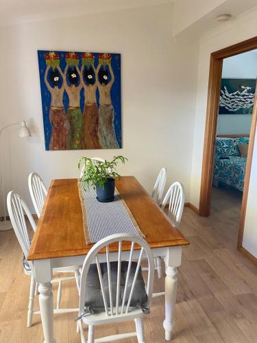 a dining room table with white chairs and a painting at Bayhaven- Best deal 4 bedroom 2 bathroom getaway in Port Moonta