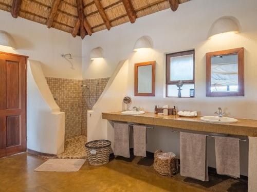 a bathroom with two sinks and a shower at Nyati Safari Lodge in Hoedspruit