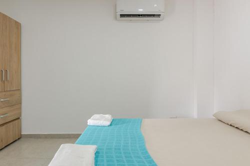 a white bedroom with a bed with a blue blanket at Casa Bacoba in Santa Marta