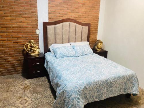 a bedroom with a bed and two nightstands and a brick wall at Cabaña rodeada de naturaleza in Pátzcuaro