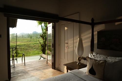 a bedroom with a bed and a view of a field at Kirindi Paddy Isle in Negombo