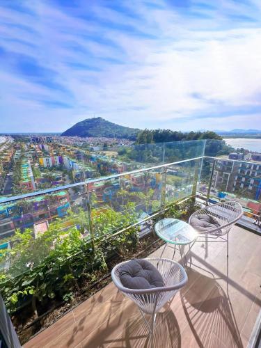 a balcony with two chairs and a view of a city at Flamingo Hai Tien in Nam Khê