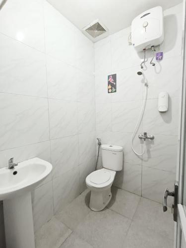 a white bathroom with a toilet and a sink at Yutaka Inn Mahveen Suhat in Blimbing