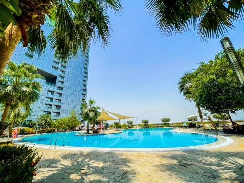 a swimming pool in front of a tall building at Voyage One Bedroom In Arc Tower Reem Island in Abu Dhabi