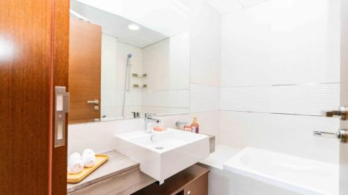a white bathroom with a sink and a mirror at Voyage One Bedroom In Arc Tower Reem Island in Abu Dhabi