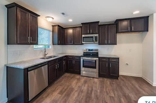 a kitchen with wooden cabinets and a counter top at Upscale King 3BR Townhouse Mins to Cary & NC State in Raleigh