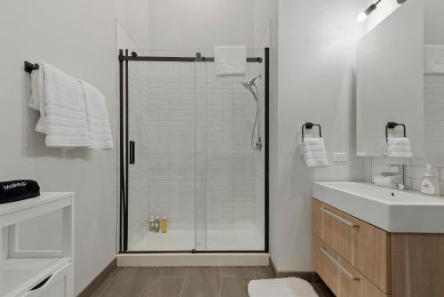 a white bathroom with a shower and a sink at Experience Downtown Chicago at Millennium - Luxury Apartments in The Loop in Chicago