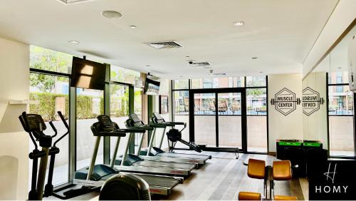 a gym with a row of treadms and elliptical machines at Enjoy a Modern and Trendy apartment in the Heart of Dubai in Dubai