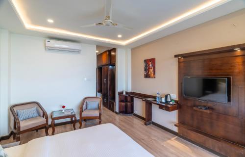 a hotel room with a bed and a flat screen tv at Karnika Resort Levelup Boutique-Dharamshala in Dharmsala