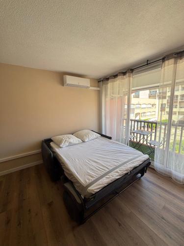 un lit dans une chambre avec une grande fenêtre dans l'établissement Studio Le saint Clair centre port, au Cap d'Agde