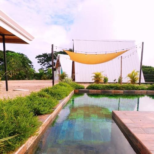 a swimming pool in front of a house with a hammock above it at Blue Sky Lodge in Nicoya