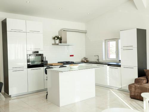 a white kitchen with white cabinets and a counter at Lux House Olga in Ruma