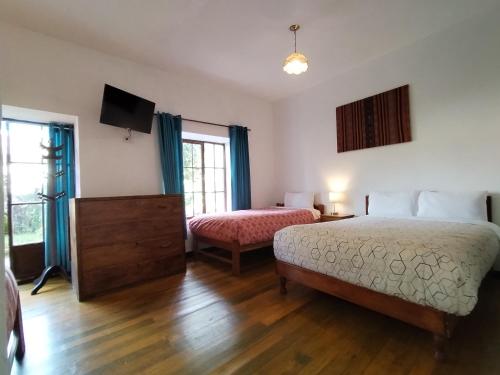a hotel room with two beds and a television at El Jardín de Jeni in Cusco