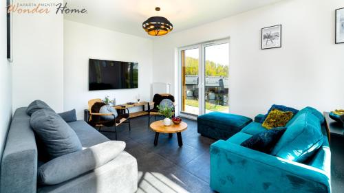 a living room with blue couches and a table at Wonder Home Myśliwska - Domki przy stoku Karpatka - na terenie kompleksu plac zabaw, zewnętrzna siłownia i sklep in Karpacz
