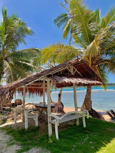 a beach with two chairs and a straw umbrella and palm trees at Sagga Homestay in Katiet