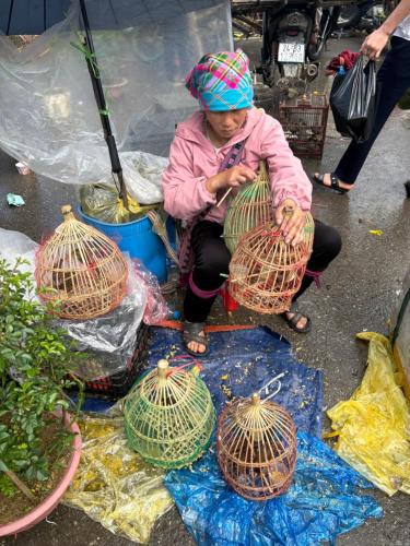 a woman sitting next to birds in bird cages at maison Rose & Jardinier eco homestay in Sa Pa