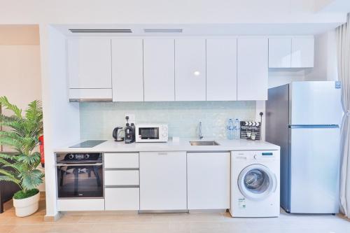 a white kitchen with a refrigerator and a dishwasher at Voyage Studio In Mayan in Abu Dhabi