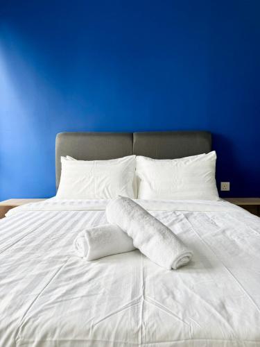 a white bed with two pillows and a blue wall at Alinea Suites by Moka in Shah Alam