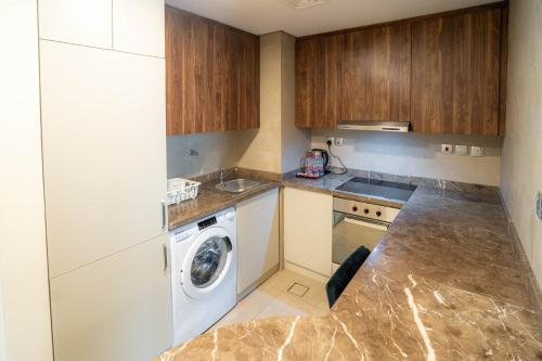 a kitchen with a washer and a washing machine at Saray Deluxe Hotel Apartments in Abu Dhabi