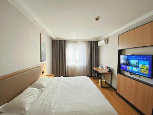a hotel room with a bed and a flat screen tv at GreenTree Inn Taizhou New District Hospital of Renmin Hospital Mingliu Express Hotel in Jiuligou