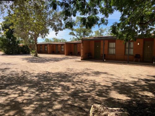 a row of brown buildings with a large driveway at Territory Manor Motel & Caravan Park in Mataranka