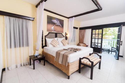 a bedroom with a large bed and a chair at PrideInn Flamingo Beach Resort & Spa Mombasa in Mombasa
